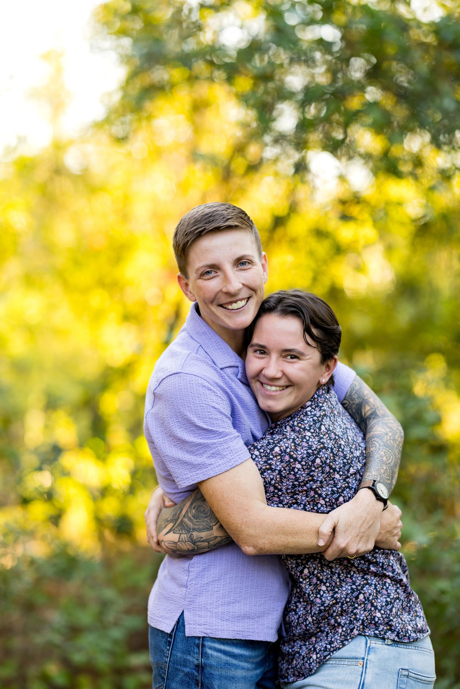 A couple embraces outdoors with warm autumn sunlight filtering through trees in the background.