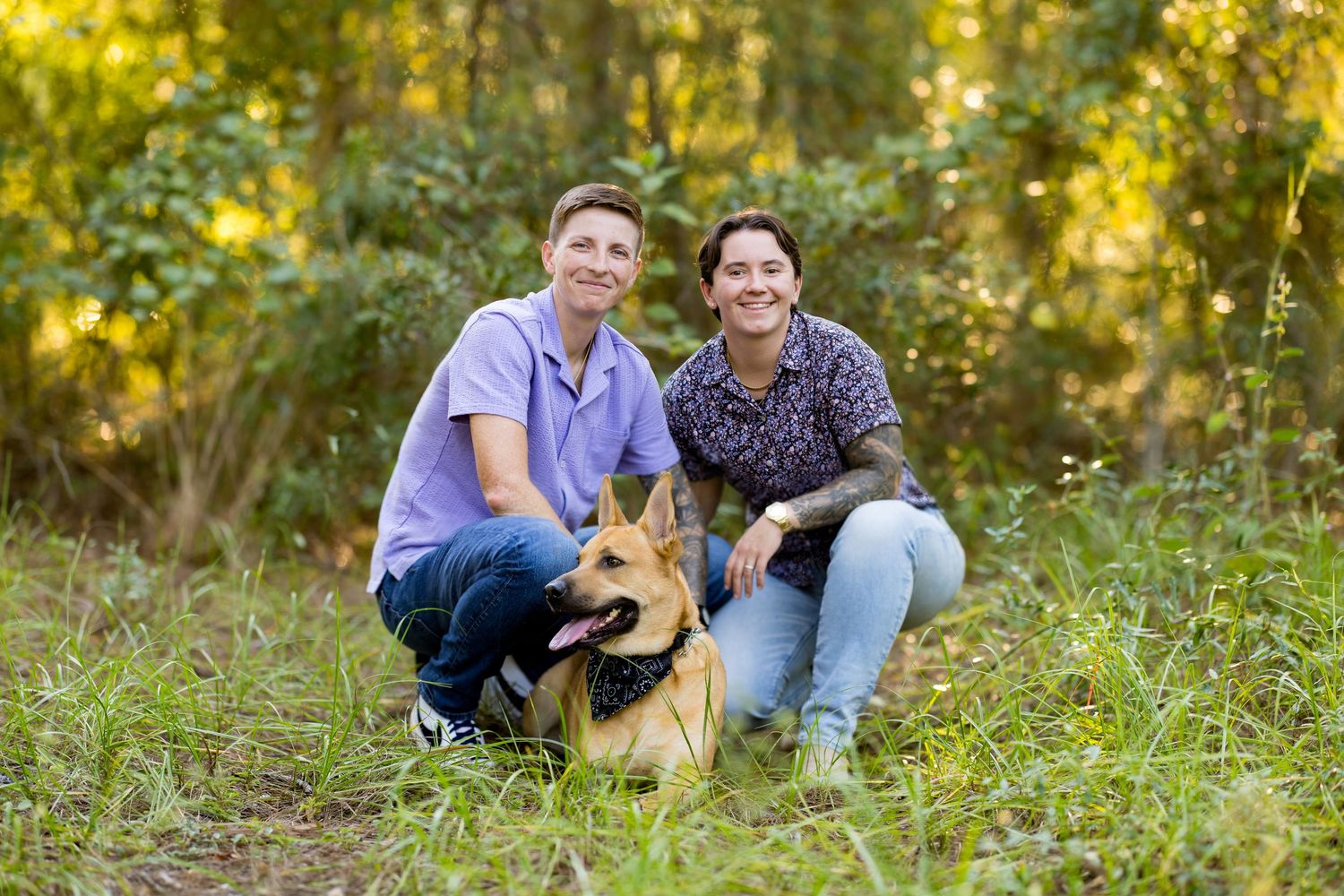 Family and dog enjoying a candid outdoor photo session in a sunlit meadow with golden autumn foliage.
