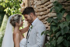 A tender moment between newlyweds against an ivy-covered stone wall.