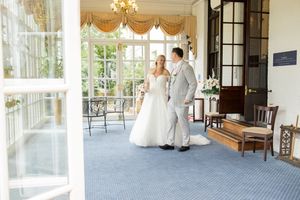 Elegant wedding venue interior with chandelier and large windows letting in natural light.