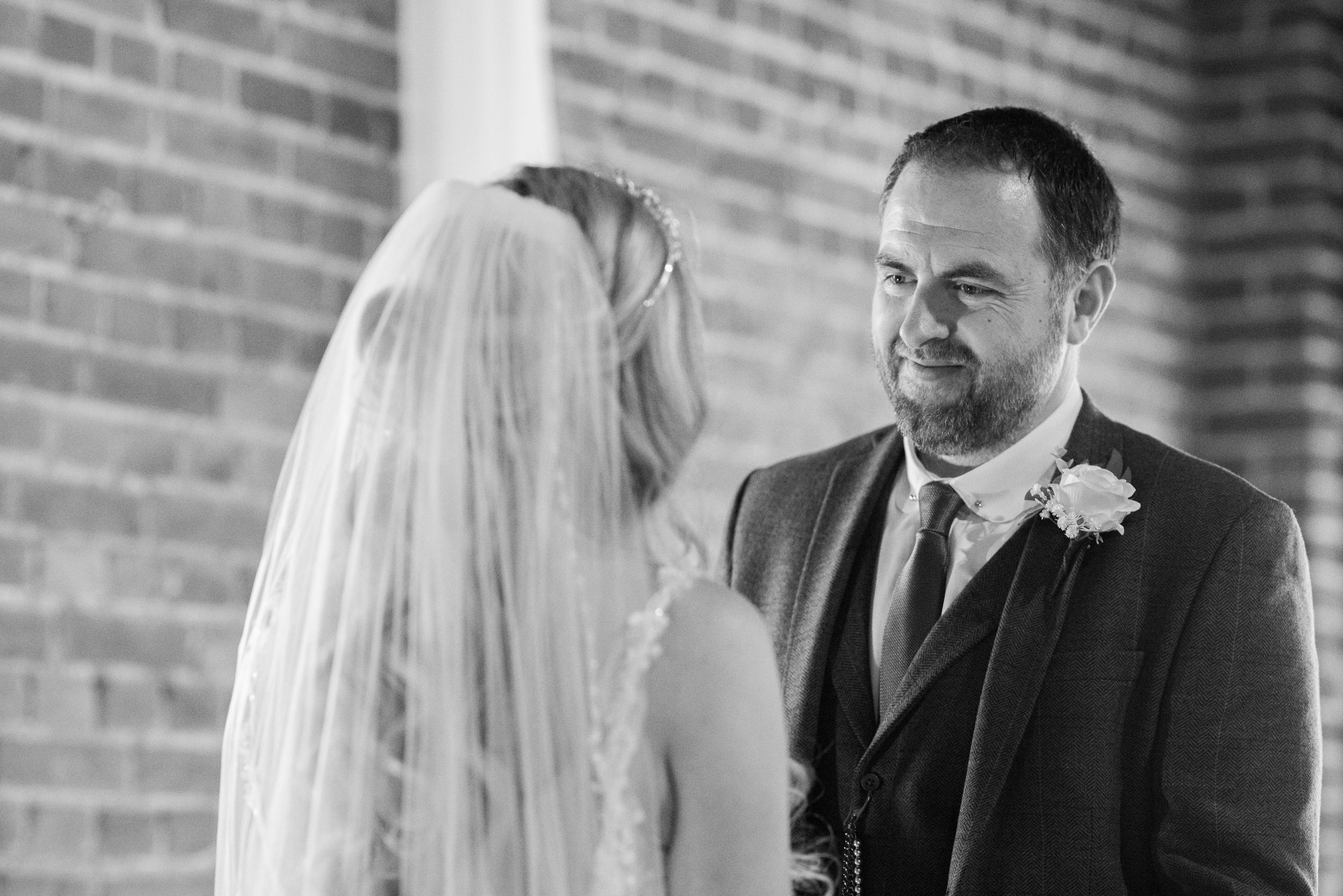 Black and white wedding ceremony moments against brick wall backdrop.