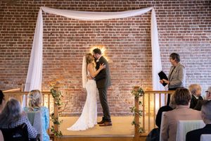 Wedding ceremony setup with white draping against exposed brick walls.