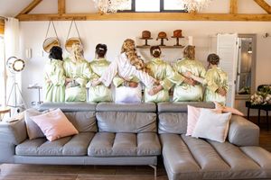 Modern wedding venue lounge area with gray sofas and rustic wooden beam ceiling.