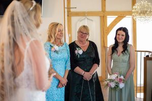 Wedding party gathered in a rustic venue with wooden beams and natural light.