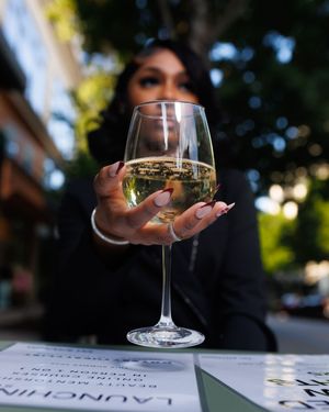 A wine glass sits on a table with menu cards and soft bokeh lighting in the background.