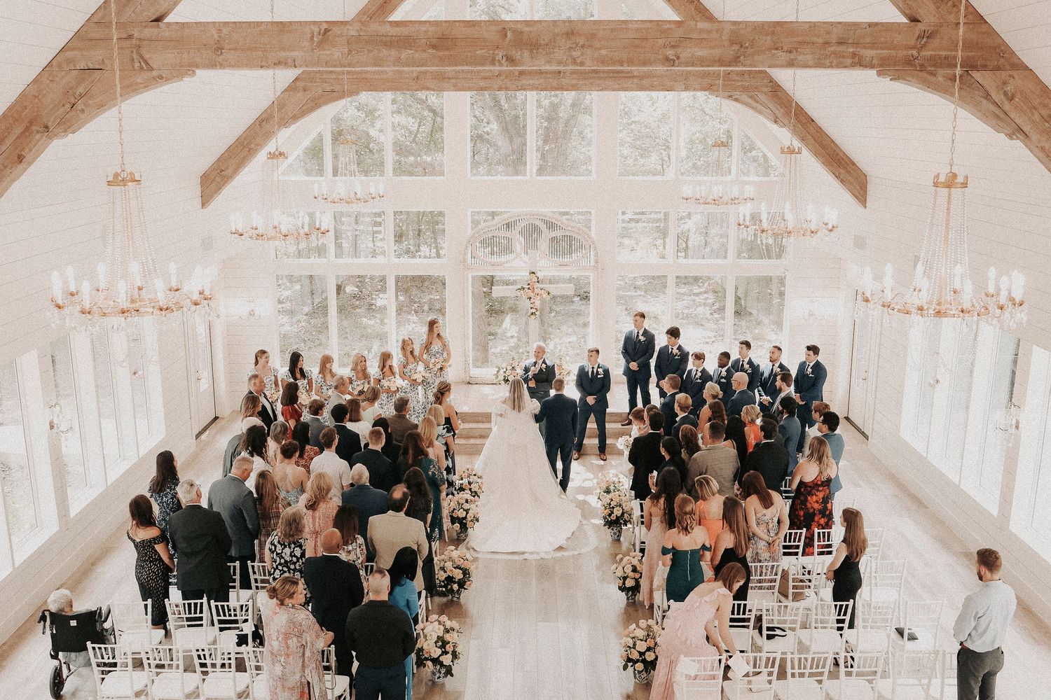 Wide view of elegant wedding ceremony with guests seated and floral aisle design