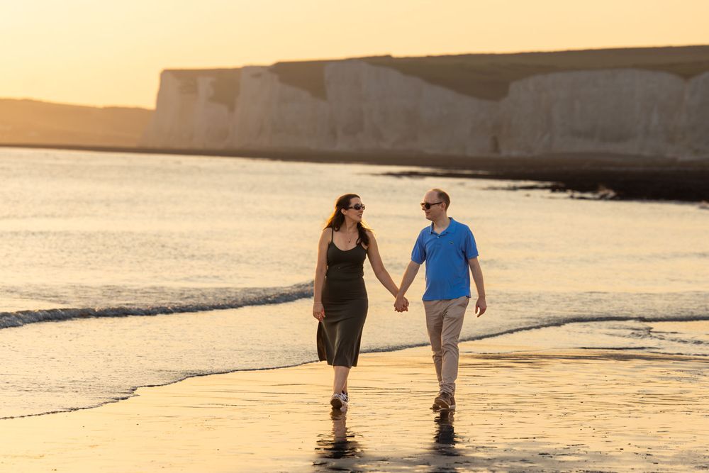 Couple paddle along Birling Gap beach, East Sussex