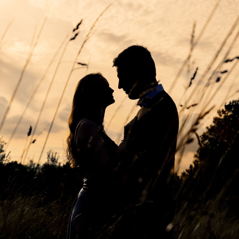 Striking silhouette of couple in Kent countryside with long grass in foreground
