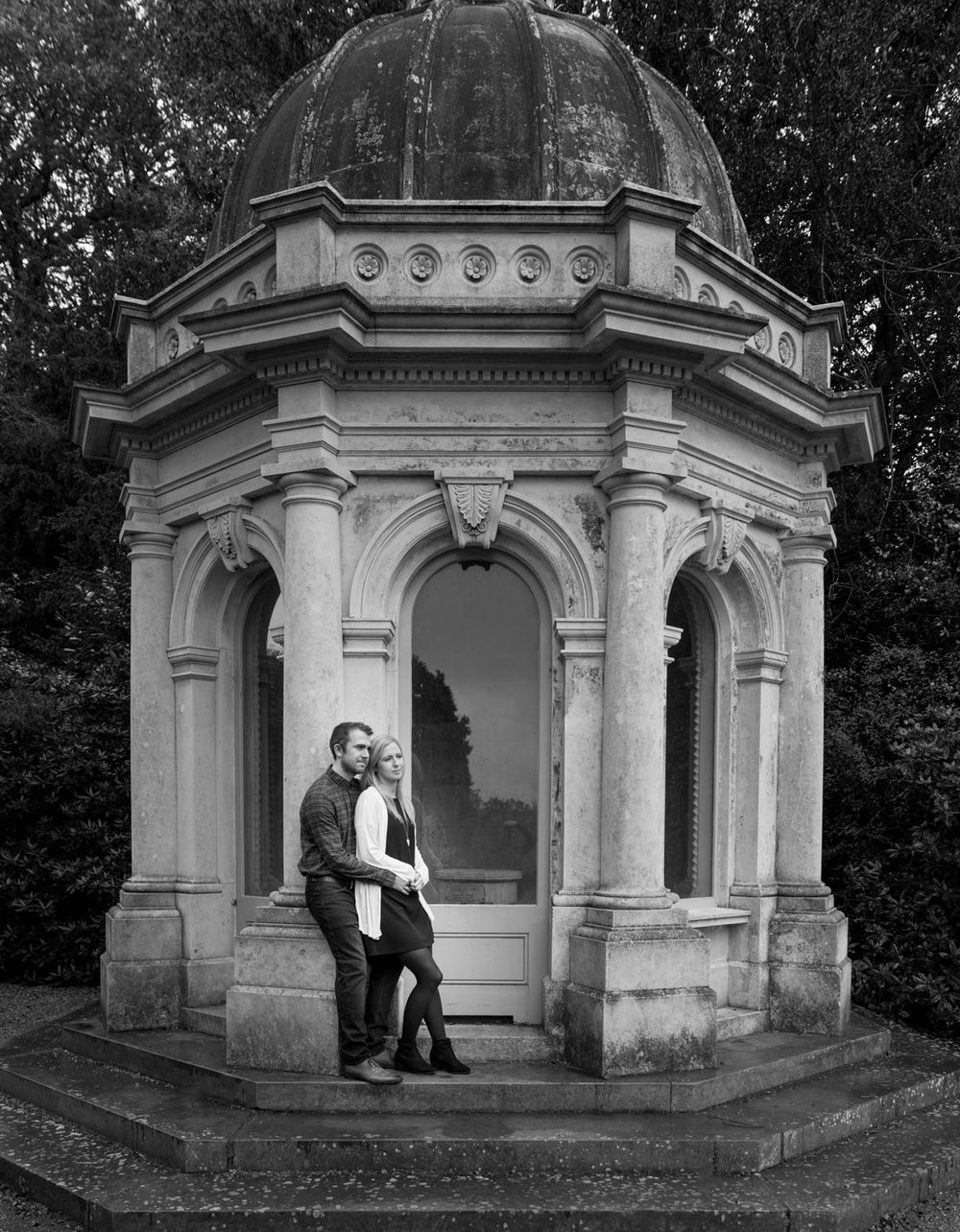 Couple leaning with each other against historic garden folly in Kent Park