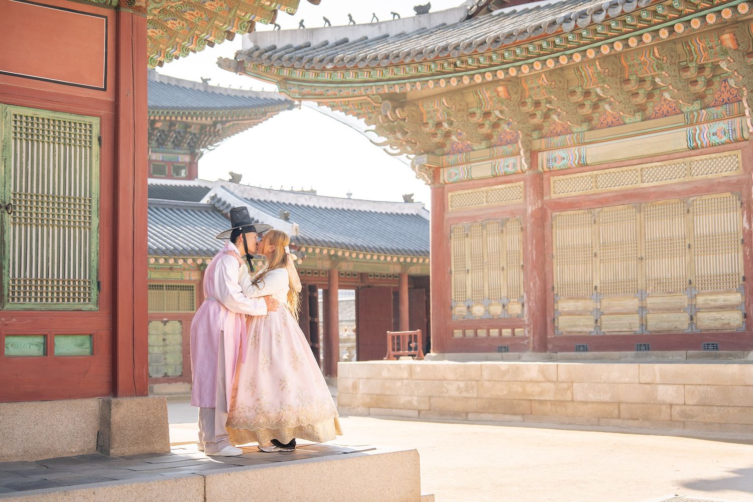 Traditional Korean hanbok dress worn at Gyeongbokgung Palace courtyard with ornate wooden architecture on sunny day.