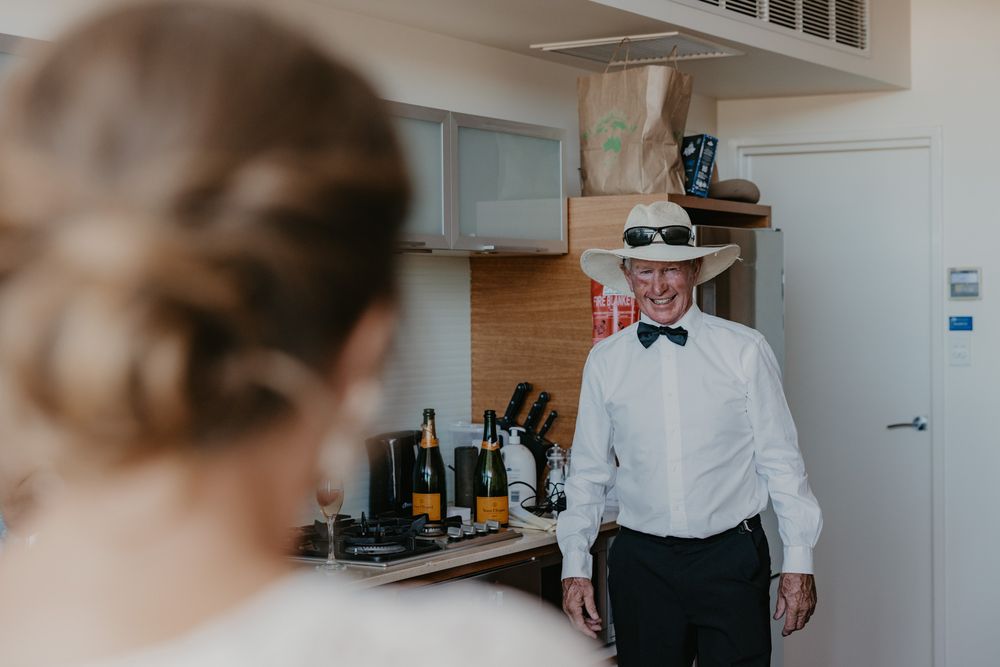 Brides father smiling at seeing her for the first time wearing wedding dress