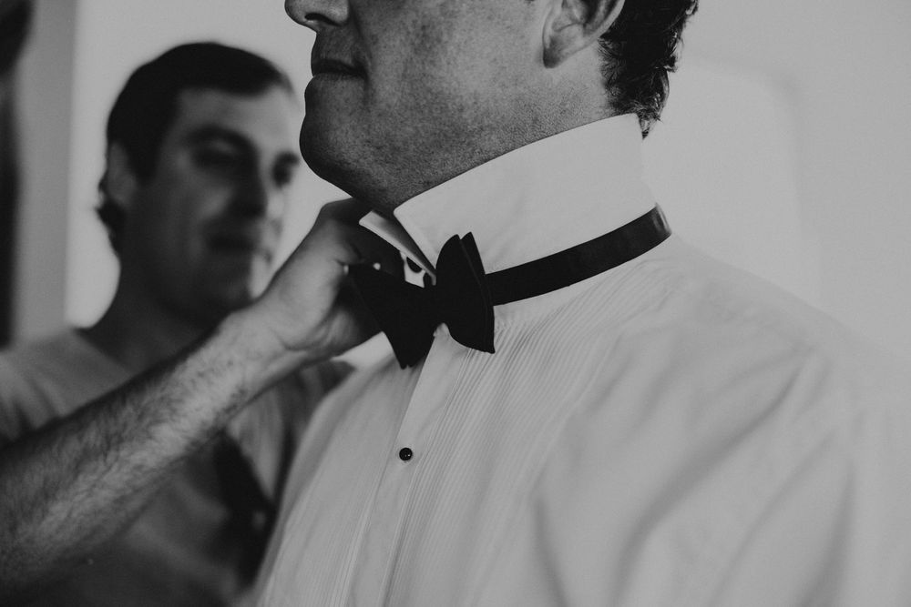 Groom having his bowtie adjusted by best man as he gets ready for wedding