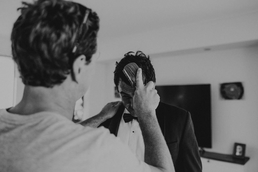 Best man brushes grooms hair prior to his wedding