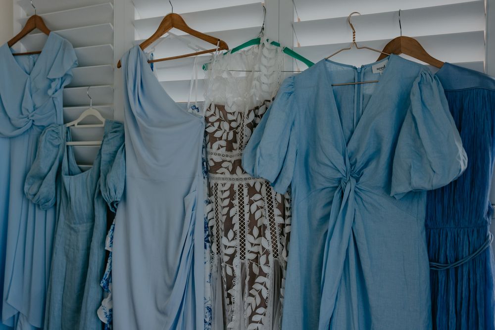 Selection of bridesmaids dresses hanging up in various shades of blues and patterns