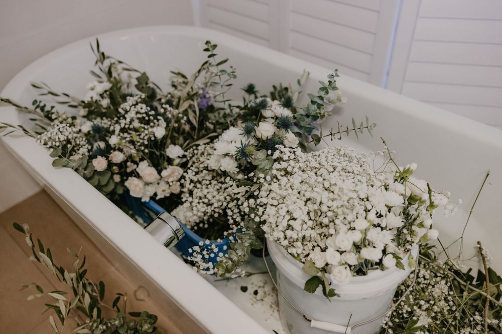 White bath full of fresh white flowers and half made wedding bouquets