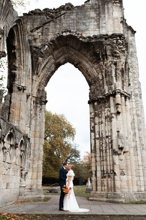 A couple embraces under the stone archways of ancient ruins during their wedding photoshoot.