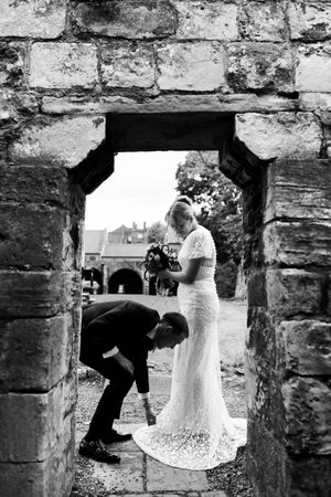 A series of black and white photos showing a couple posing through stone archways in a rustic wall.