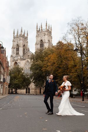 A romantic wedding couple shares a moment outside the historic York Minster cathedral on an autumn day.