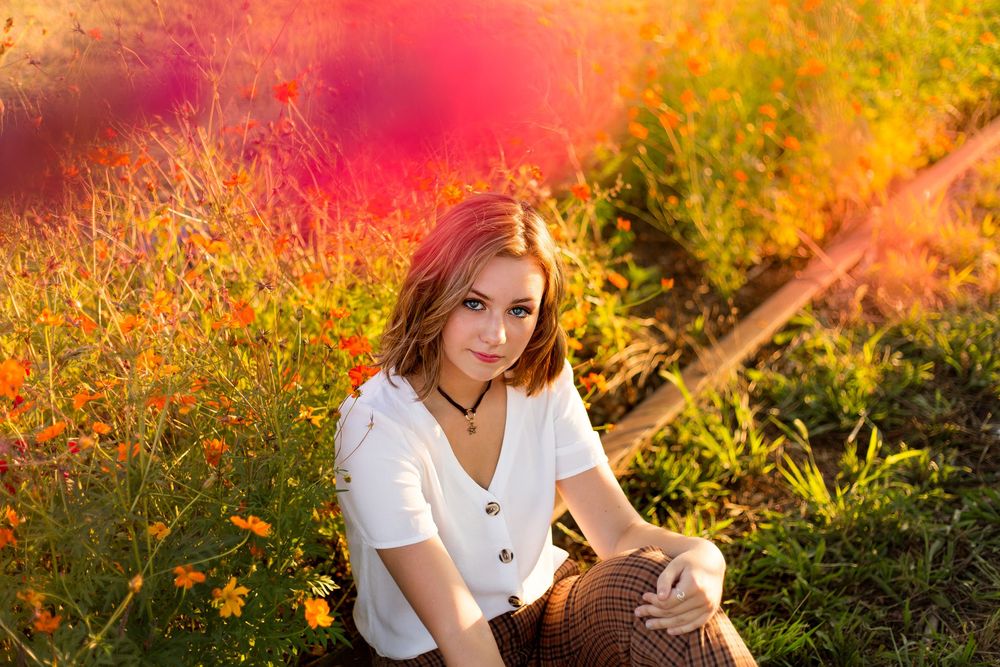 A person sits in a vibrant autumn garden with golden sunlight streaming through colorful flower foliage in Camp North End.