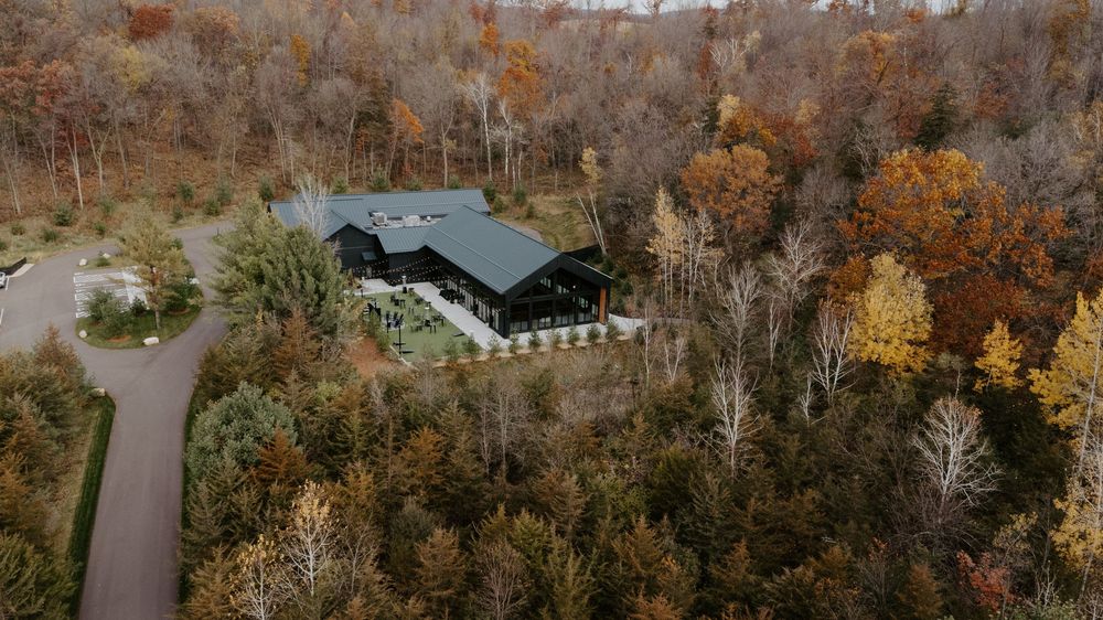 Aerial panoramic view of colorful autumn trees and buildings nestled in a rural landscape during fall season.