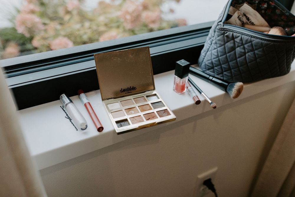 Wedding party getting ready with makeup and beauty products by a bright window.