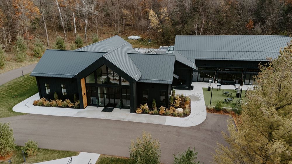 Modern black and gray architectural building with wood accents surrounded by fall foliage.