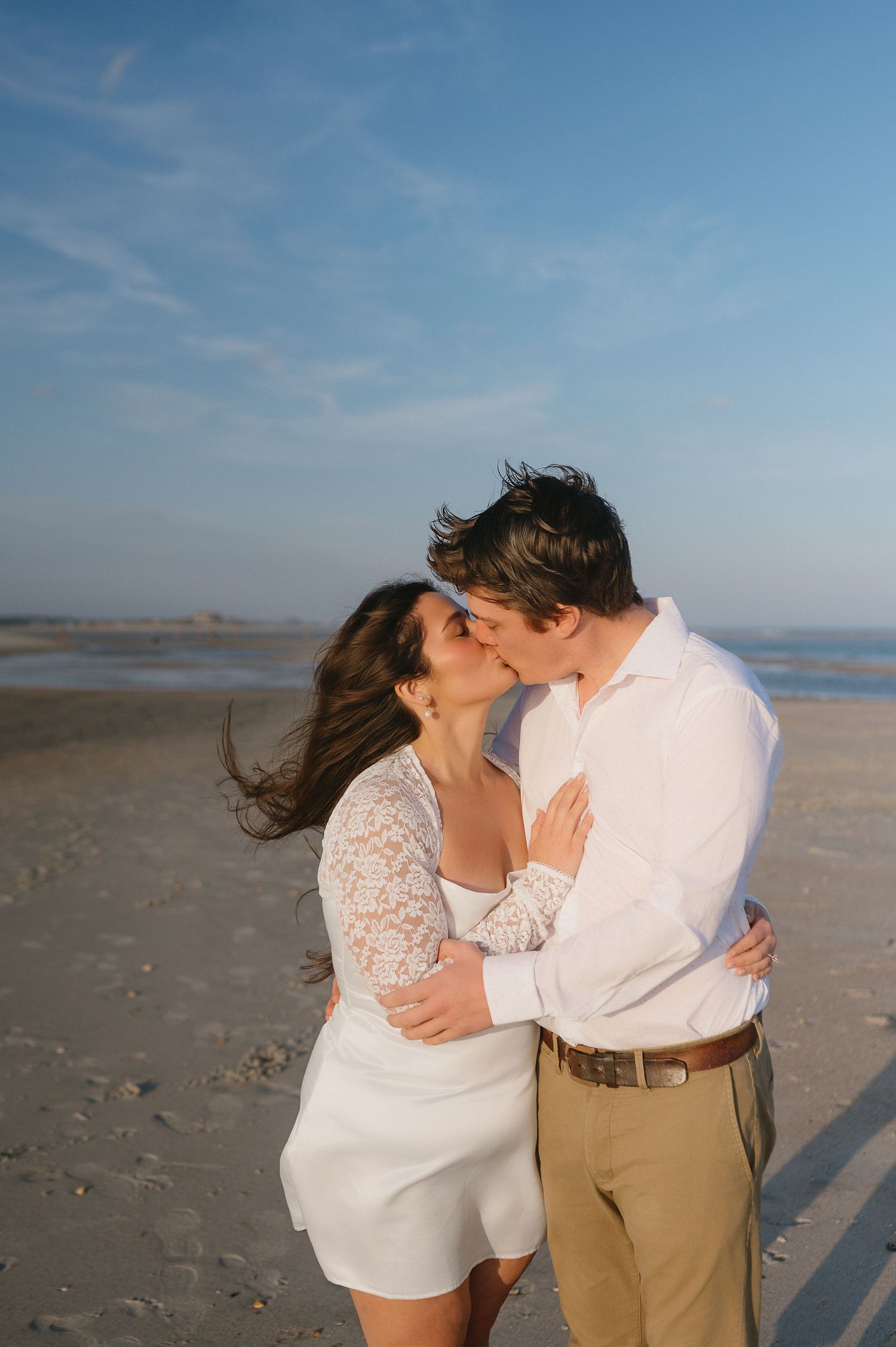 Romantic beach photography sequence capturing tender embraces against coastal landscape.