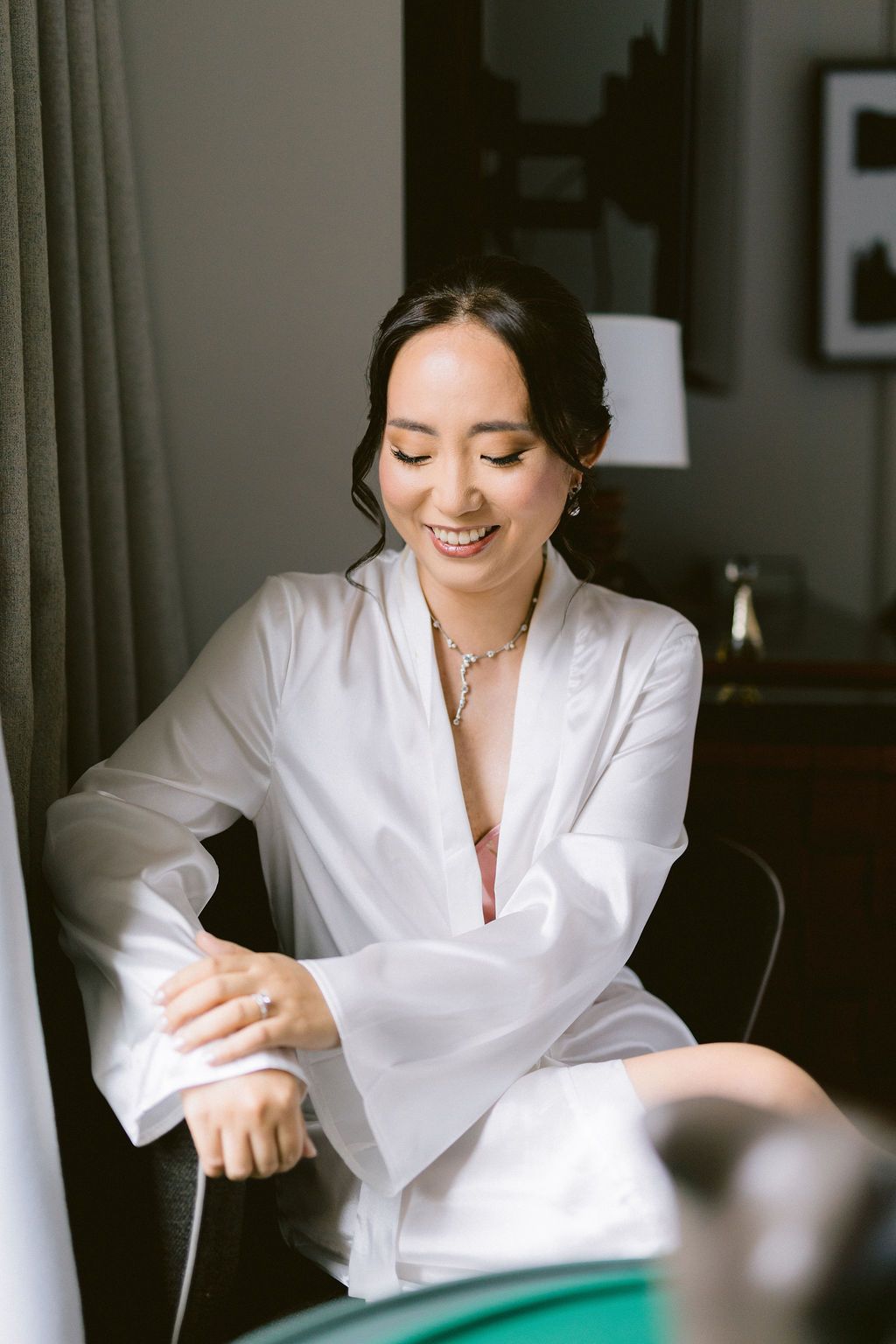 A person in a white robe smiles while writing or signing documents in a dimly lit room.