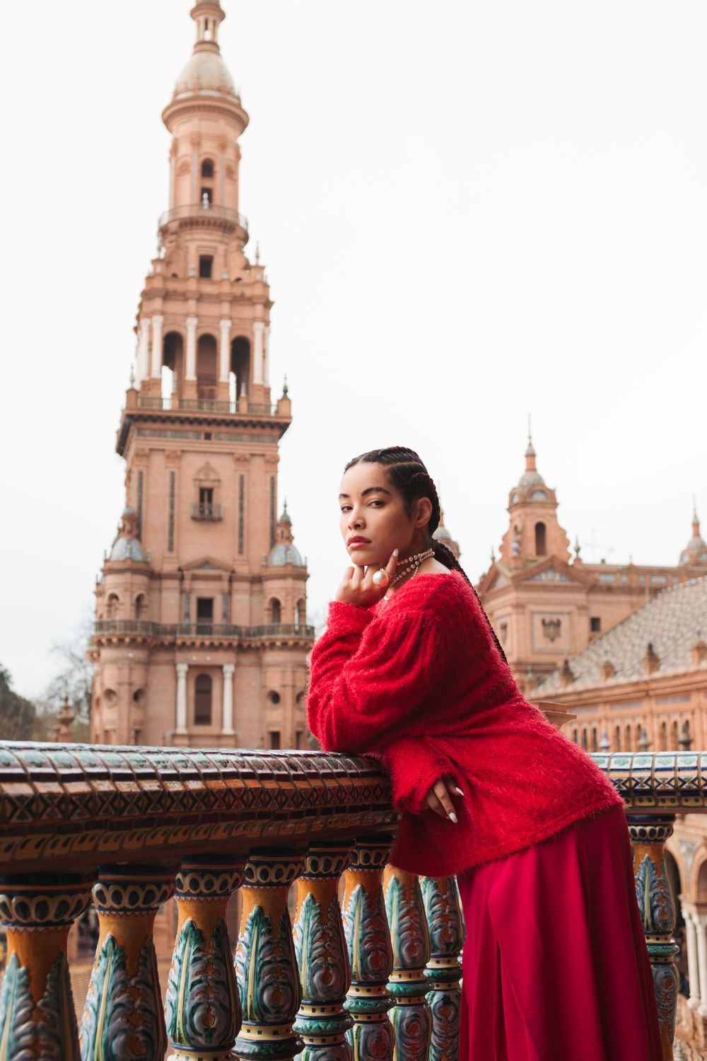 Red shawl against the stunning architecture of Plaza de España's towers and balustrades.