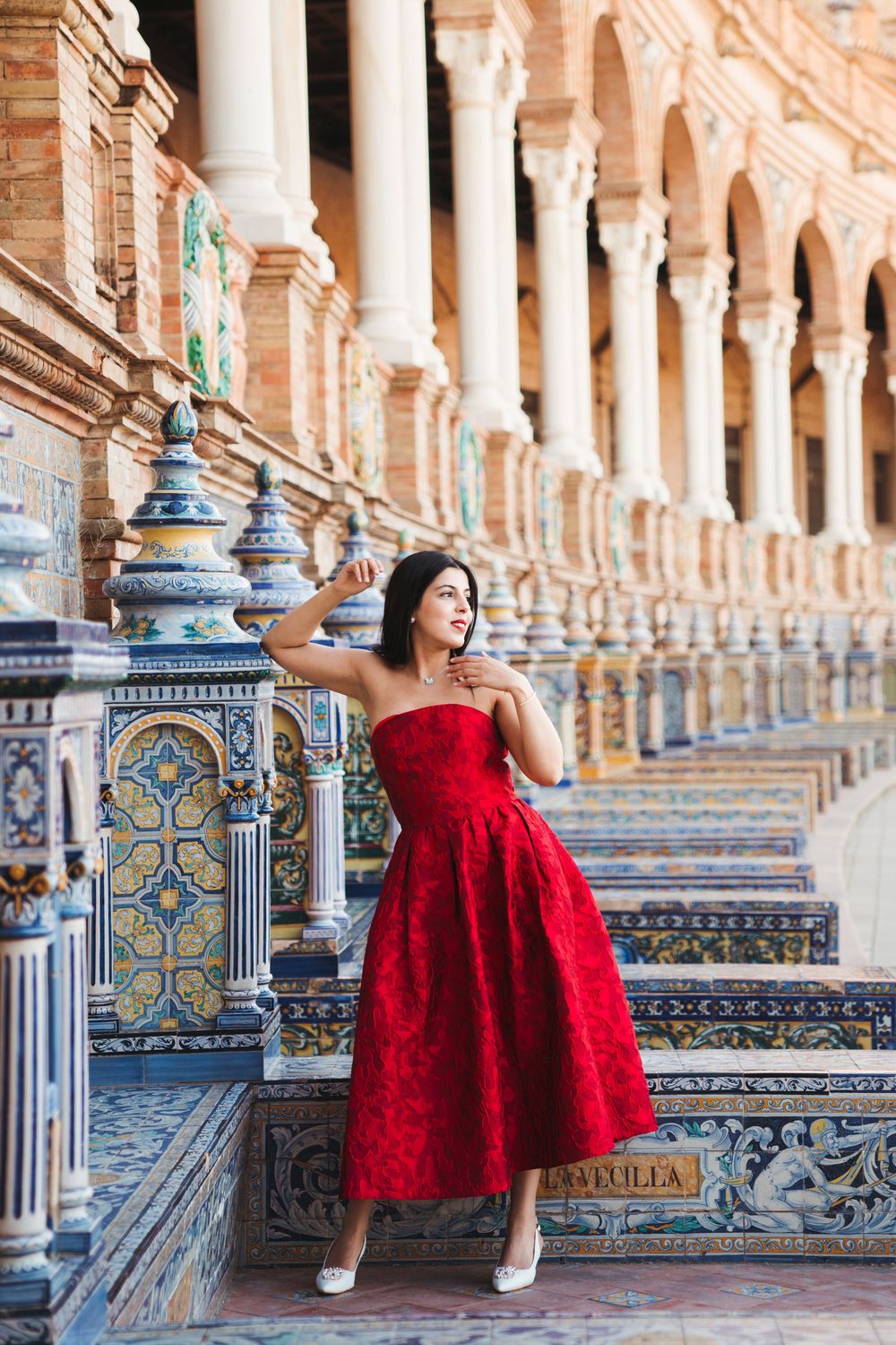 Red dress contrasts beautifully against the ornate tiles and columns of Plaza de España.