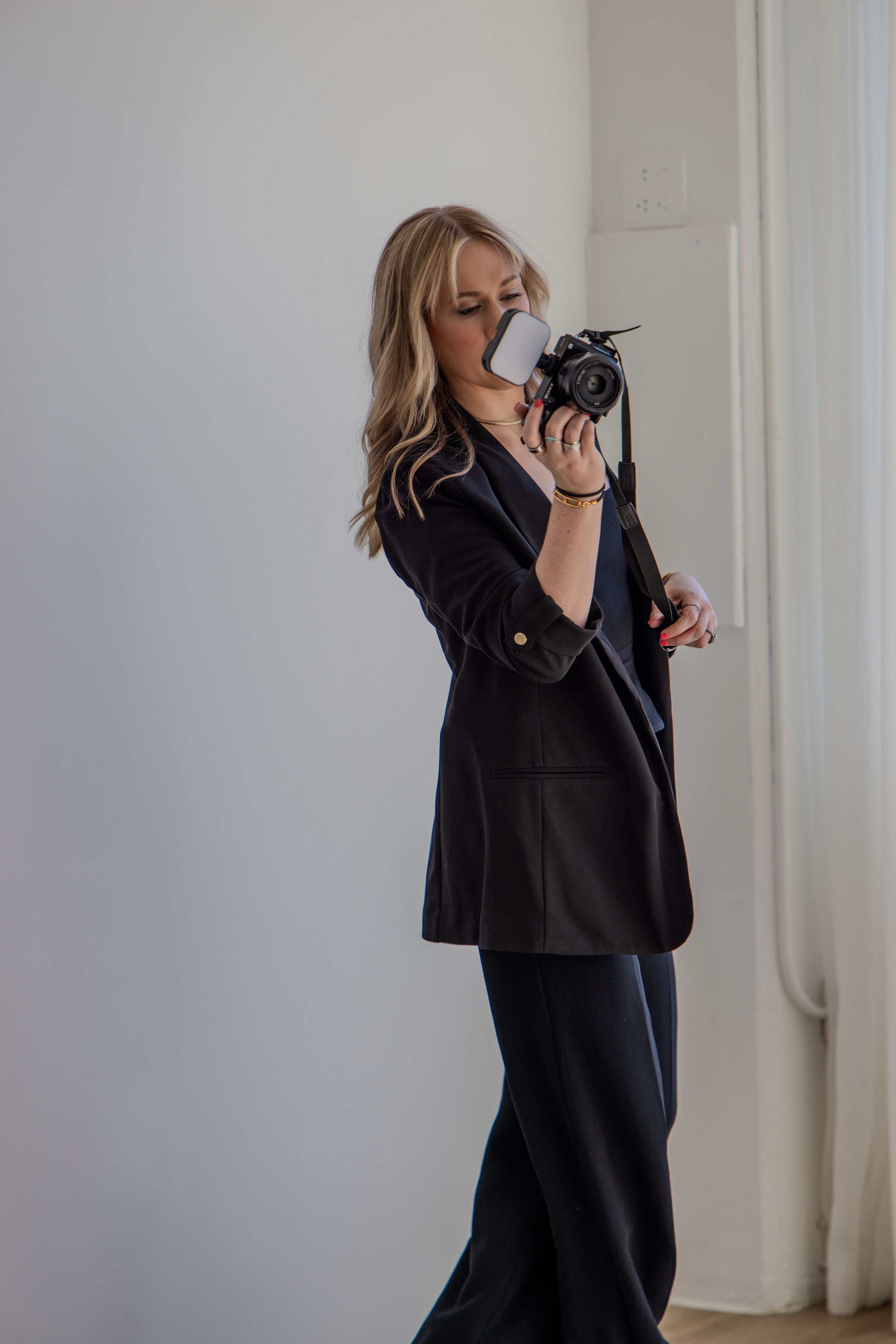 Professional in a black blazer reviewing documents and papers spread across a white desk in a modern office setting.