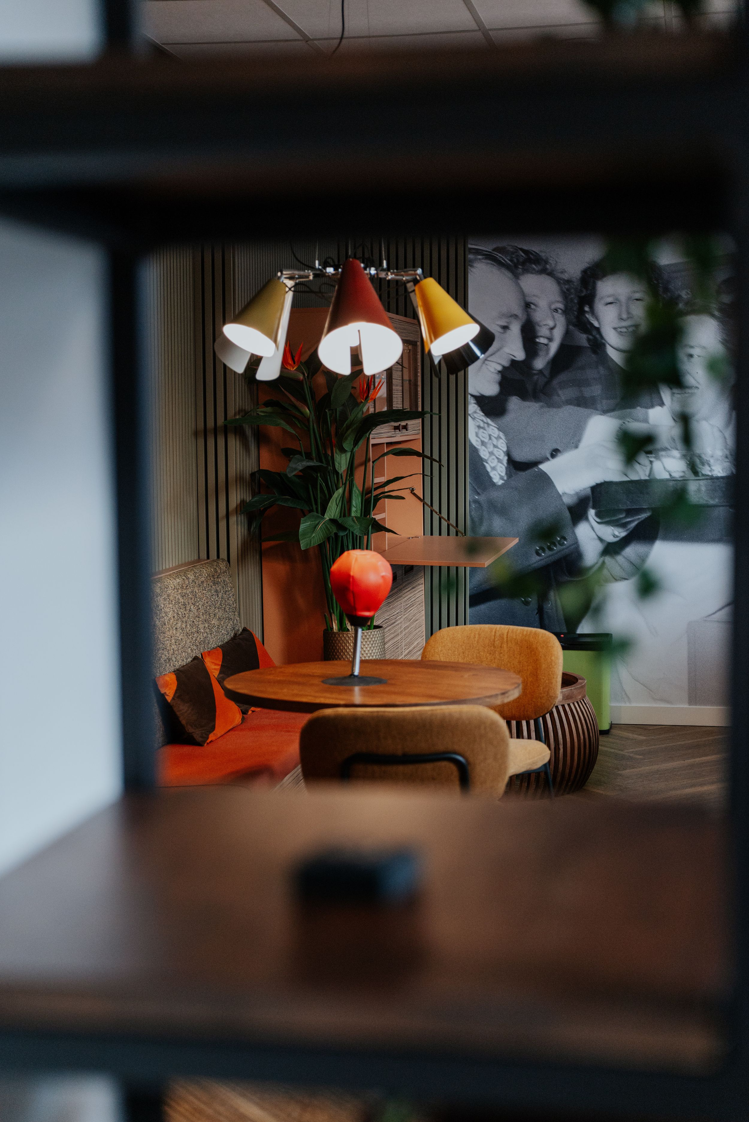 Modern living room interior with colorful retro lamp, wooden furniture and decorative artwork on wall.