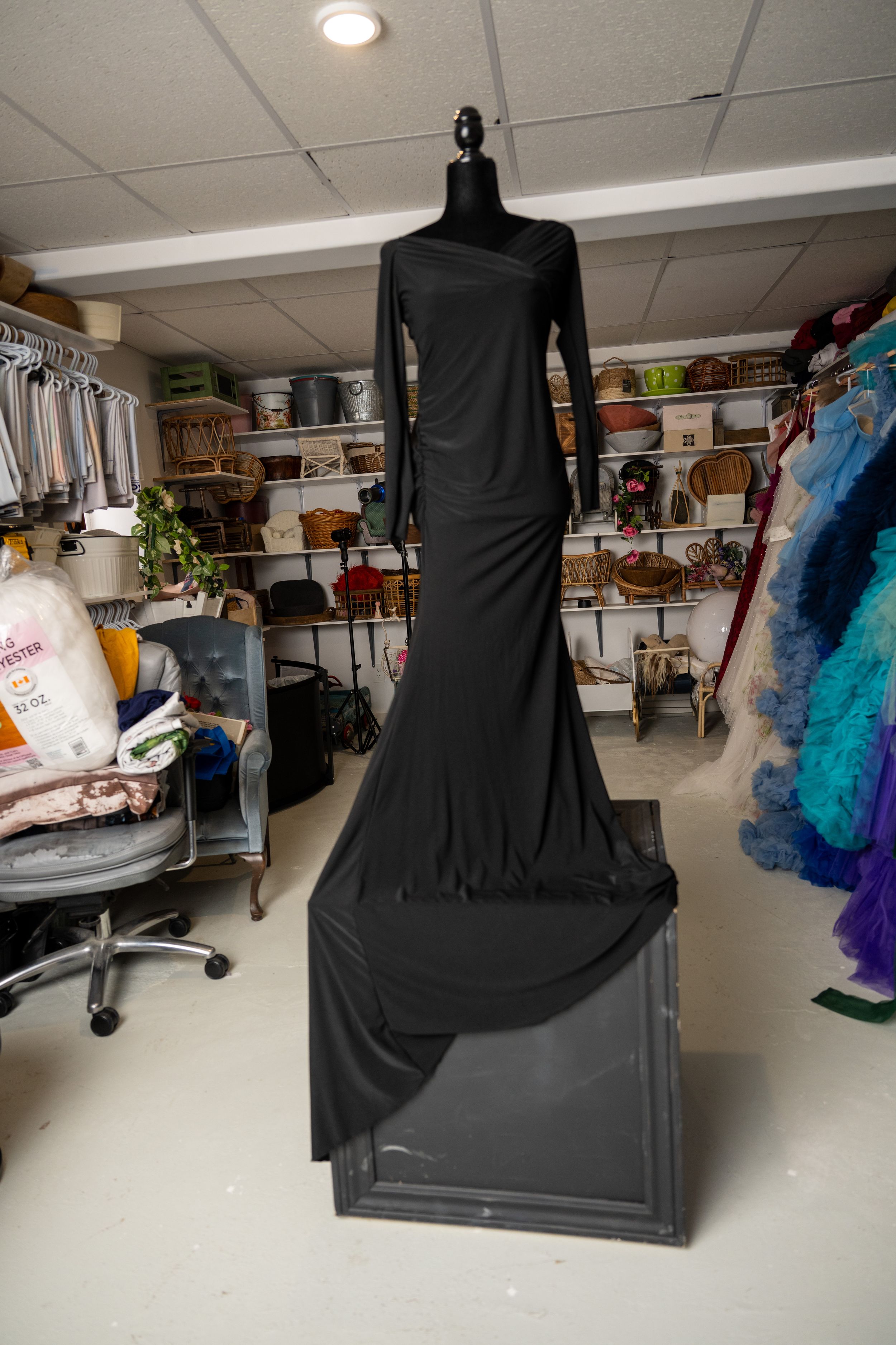 A series of black dress forms displayed in a sewing workshop with colorful tulle fabrics visible in the background.