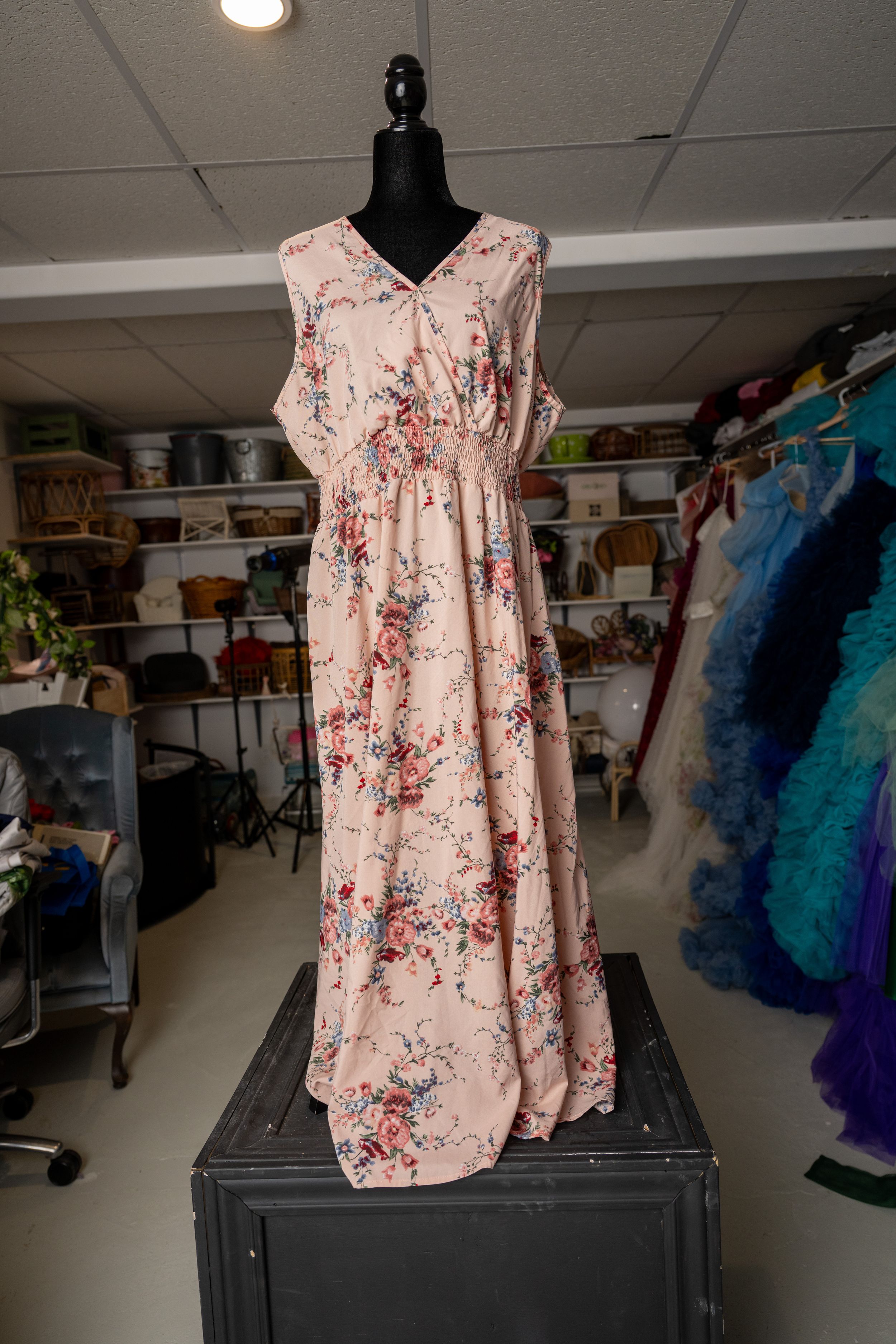 Pink floral sleeveless dress displayed on a black mannequin in a craft room or studio setting.