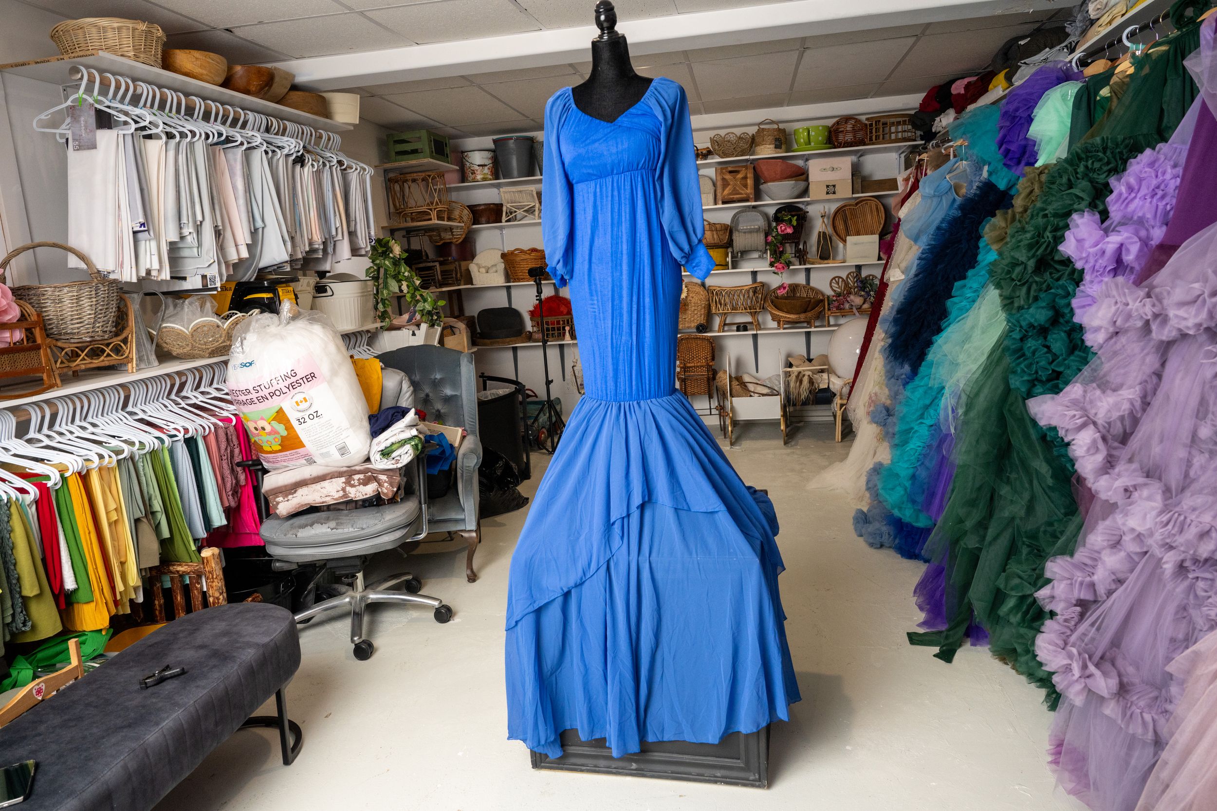 Colorful formal dresses and gowns displayed on clothing racks in a costume shop or wardrobe department.