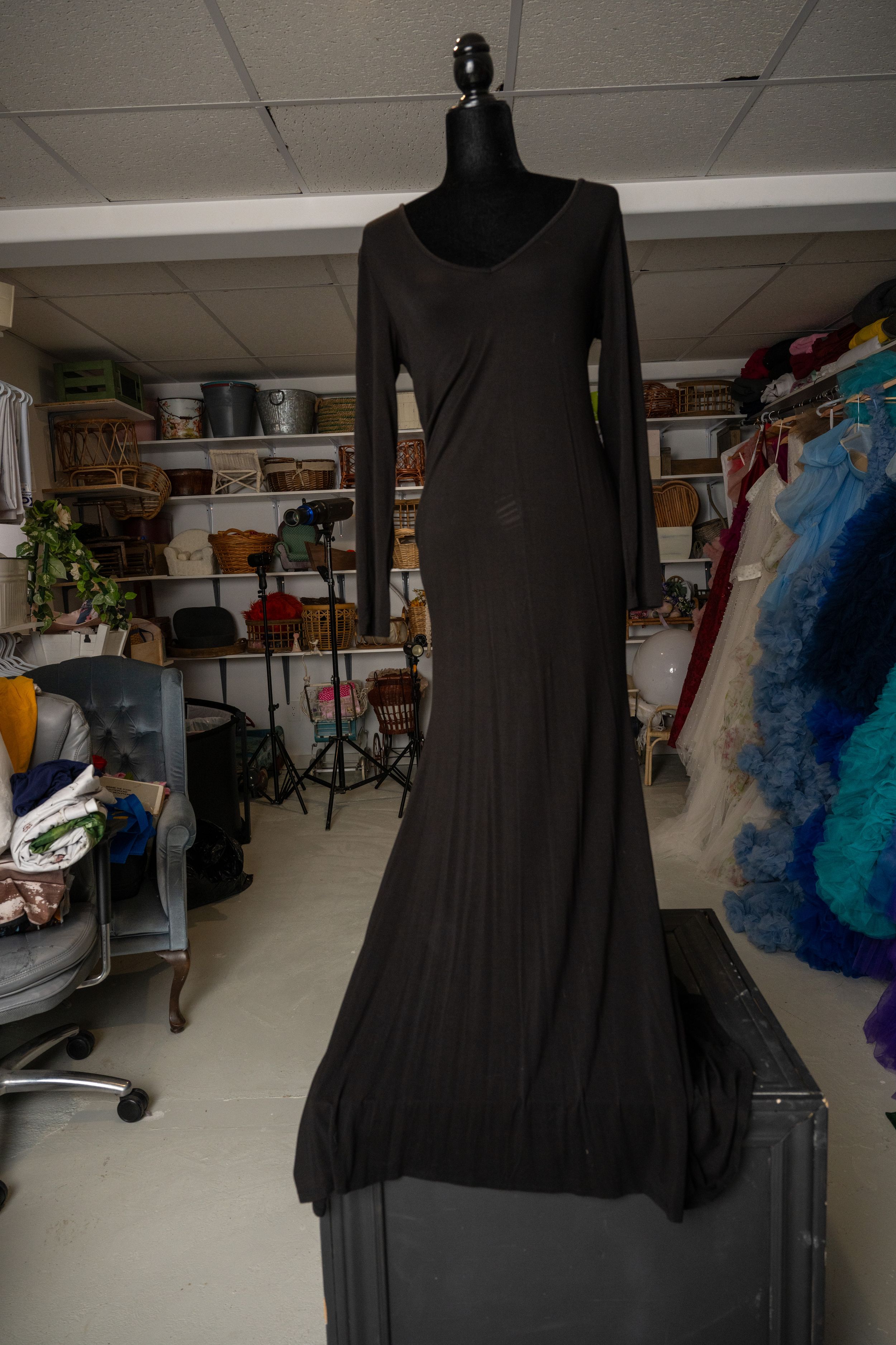 Black dress forms displayed in a sewing studio with colorful fabric and supplies visible in the background.