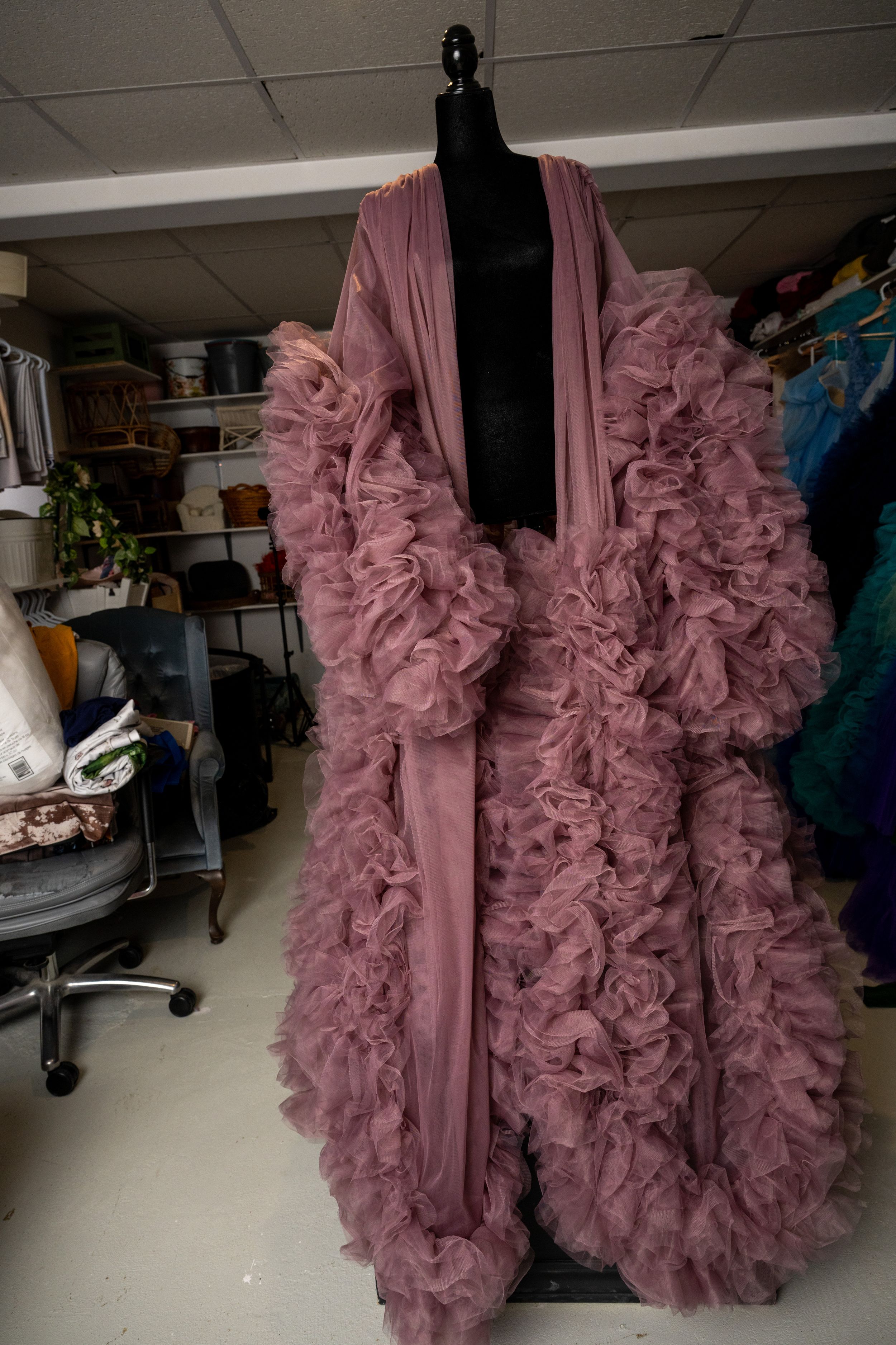 Pink ruffled tulle dress with dramatic volume displayed on a mannequin in a studio workspace.