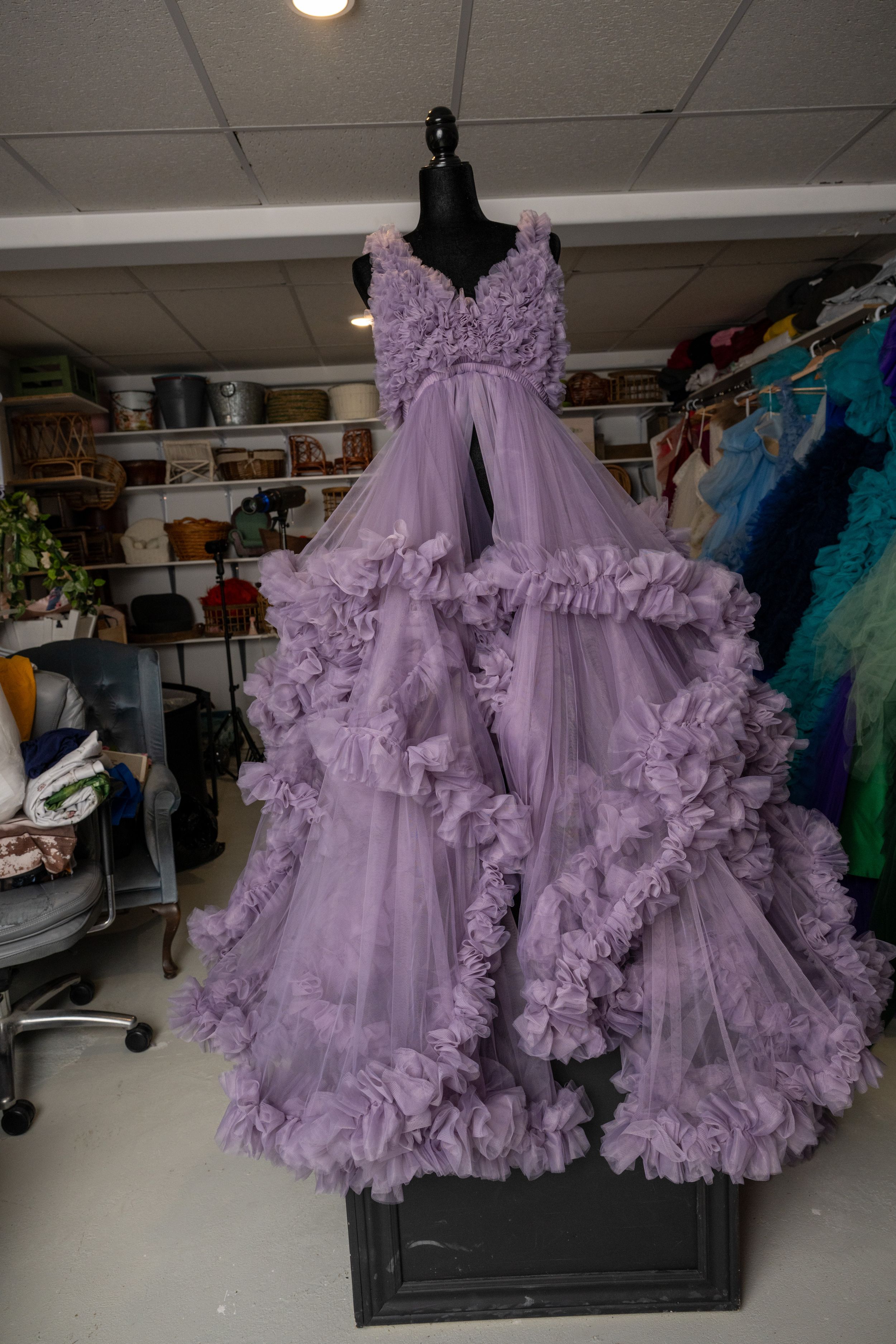 Lavender ruffled tulle ball gown with tiered skirt and floral bodice details displayed on black mannequin.