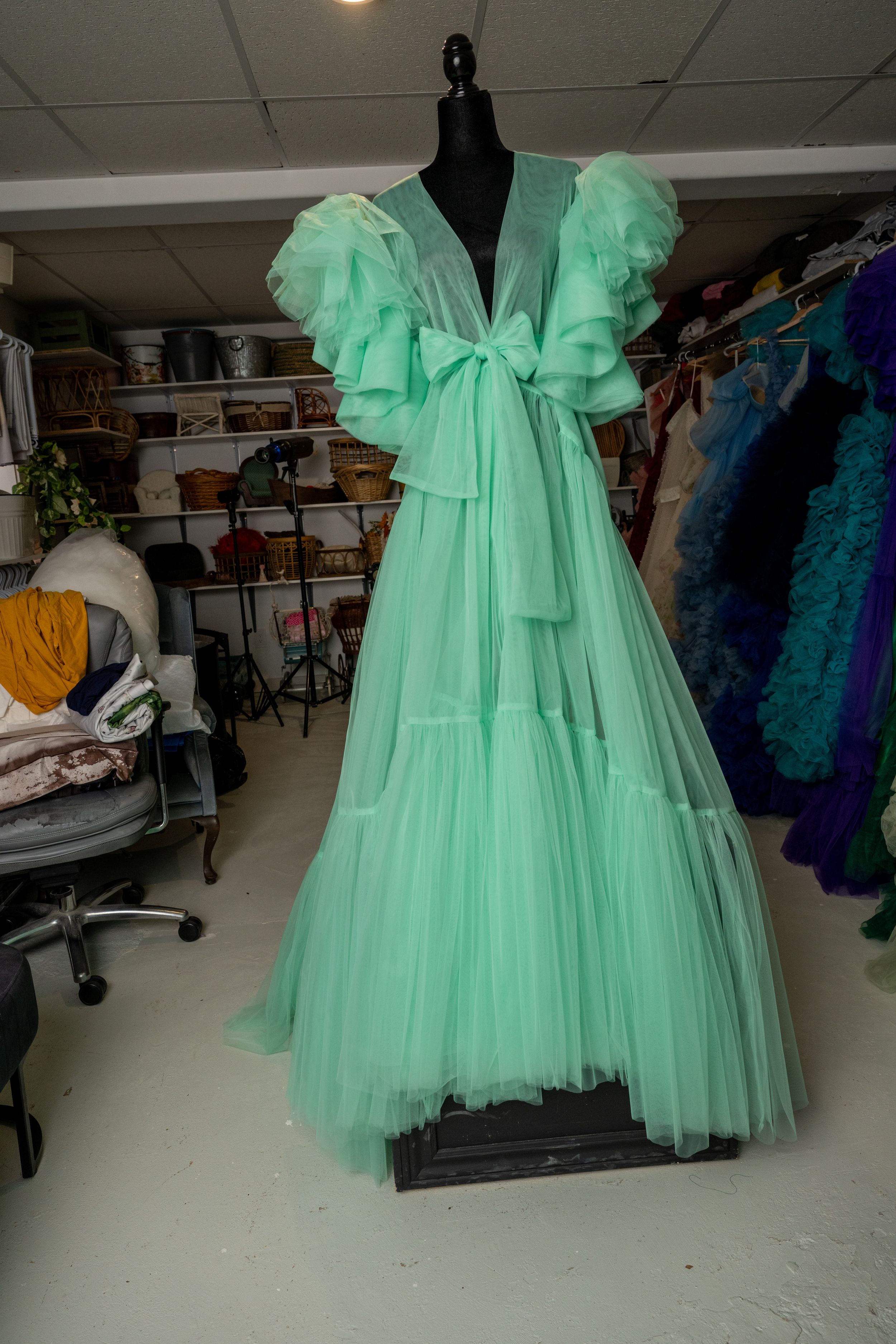 Mint green tulle ballgown dress with bow detail shown from different angles on a black mannequin in a costume shop.