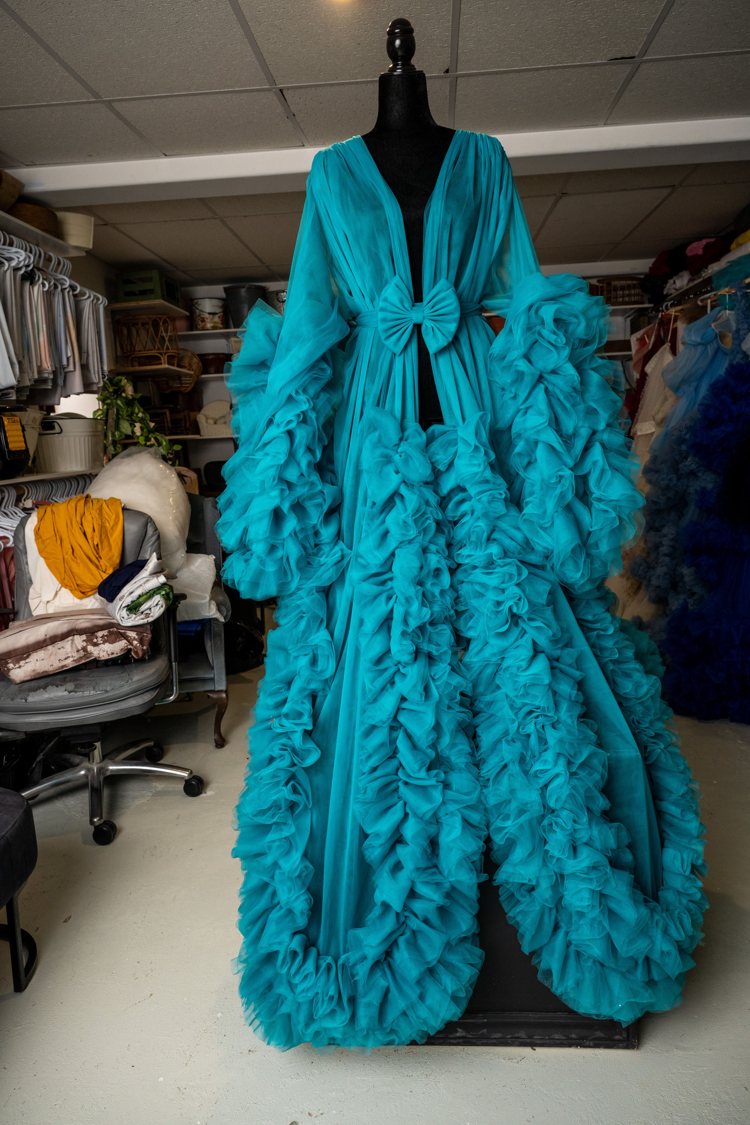 Luxurious turquoise ruffled dressing gown with dramatic sleeves and flowing tulle details displayed on a mannequin.