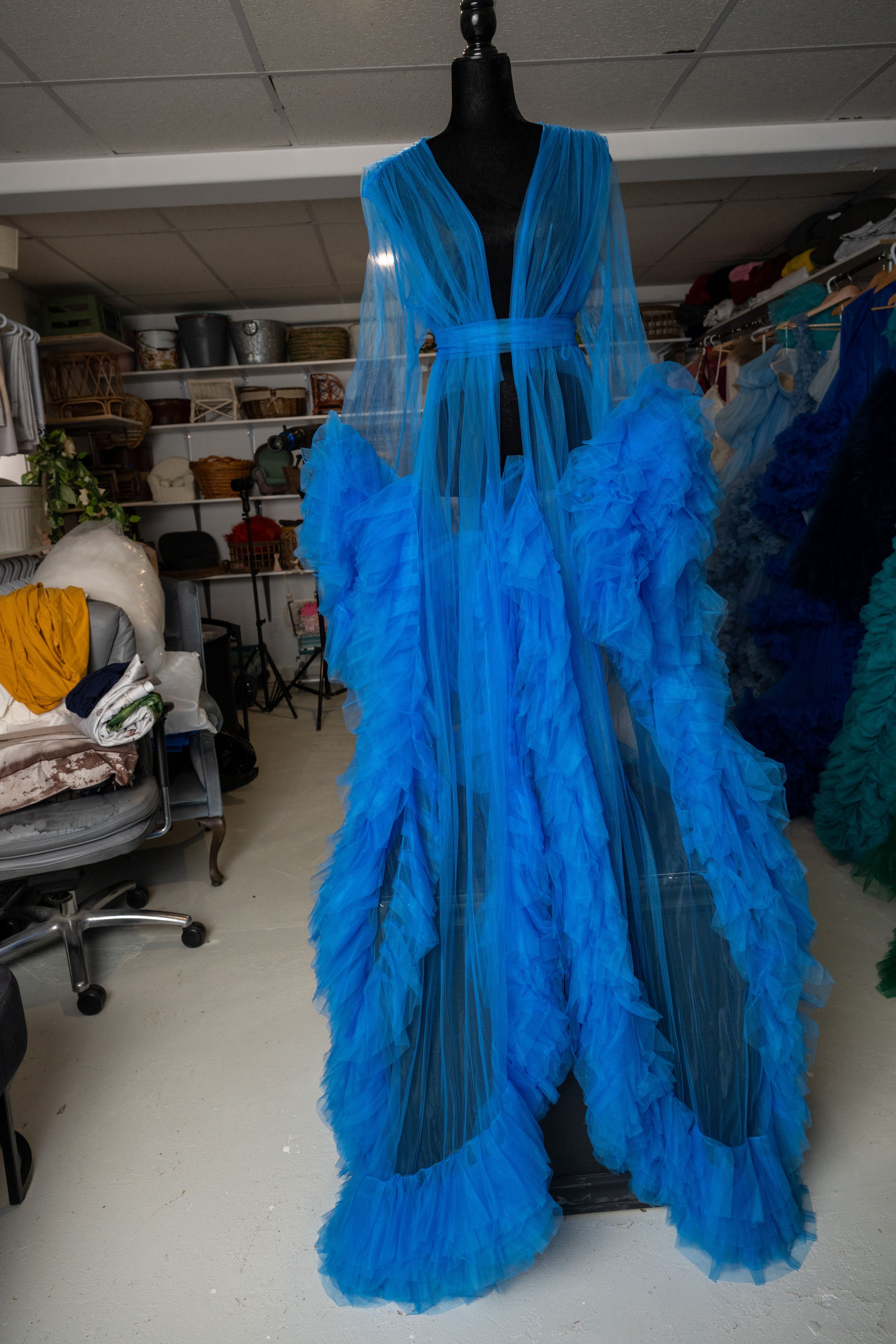 A bright turquoise blue tulle robe dress displayed on a black mannequin in a studio setting from multiple angles.