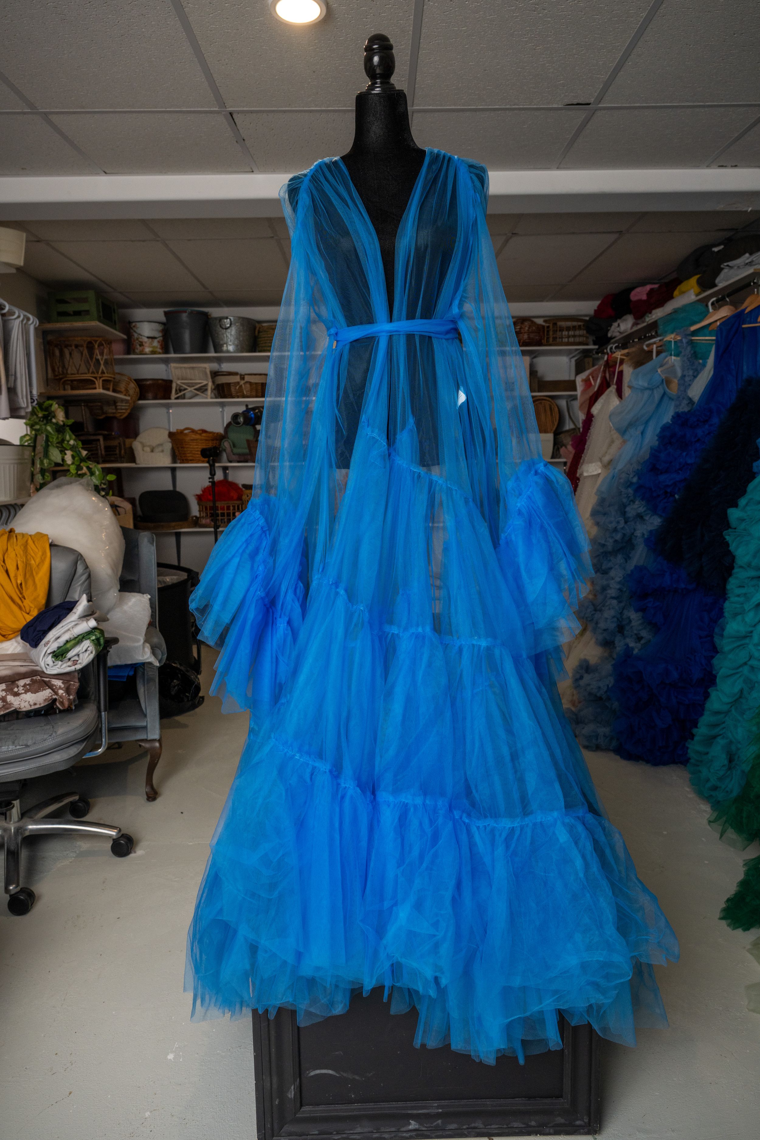 Electric blue tulle party dress with tiered skirt shown on dress form against white ceiling background.