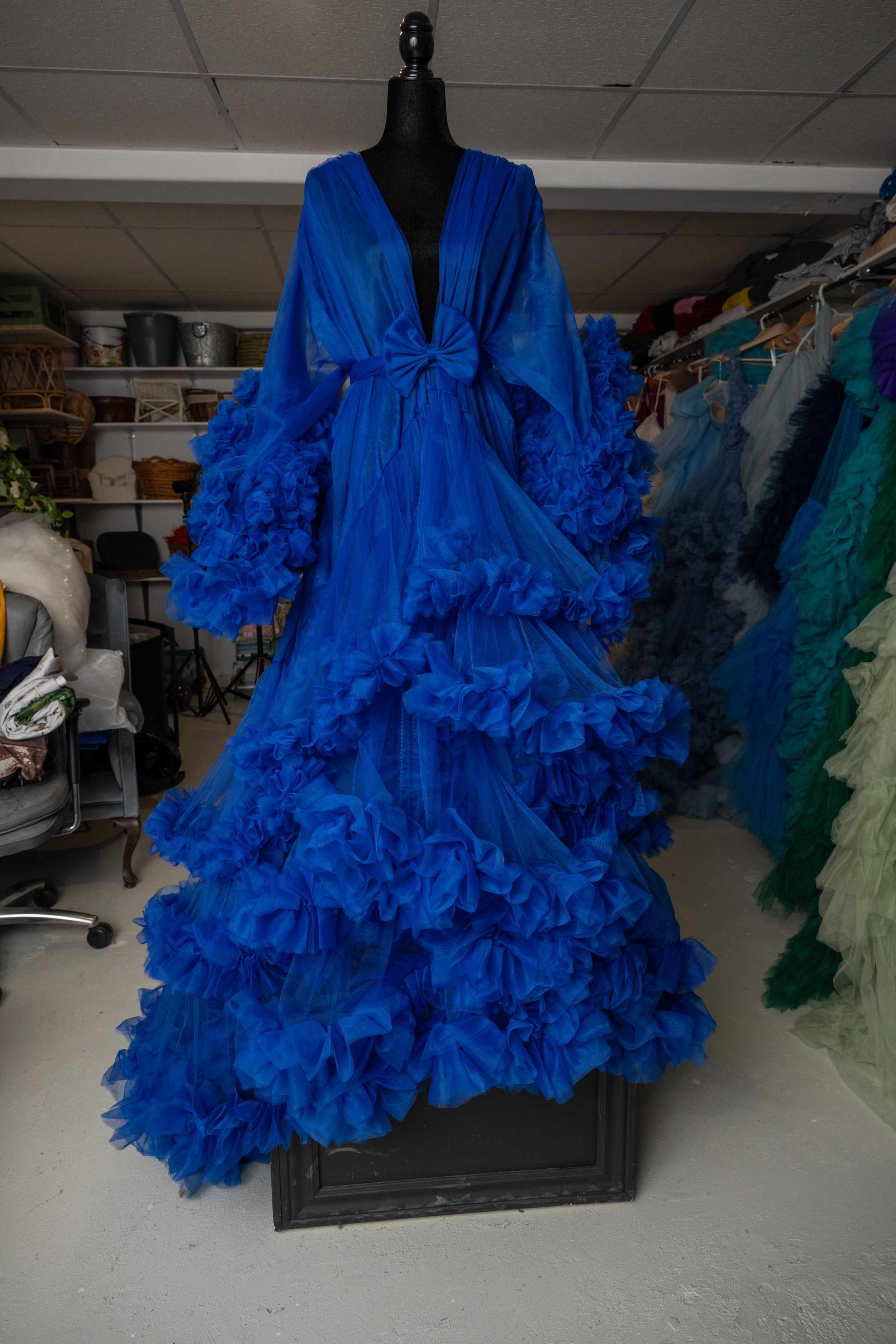 Elegant royal blue sheer robe with extravagant ruffled tulle details and tie waist displayed on a dress form.