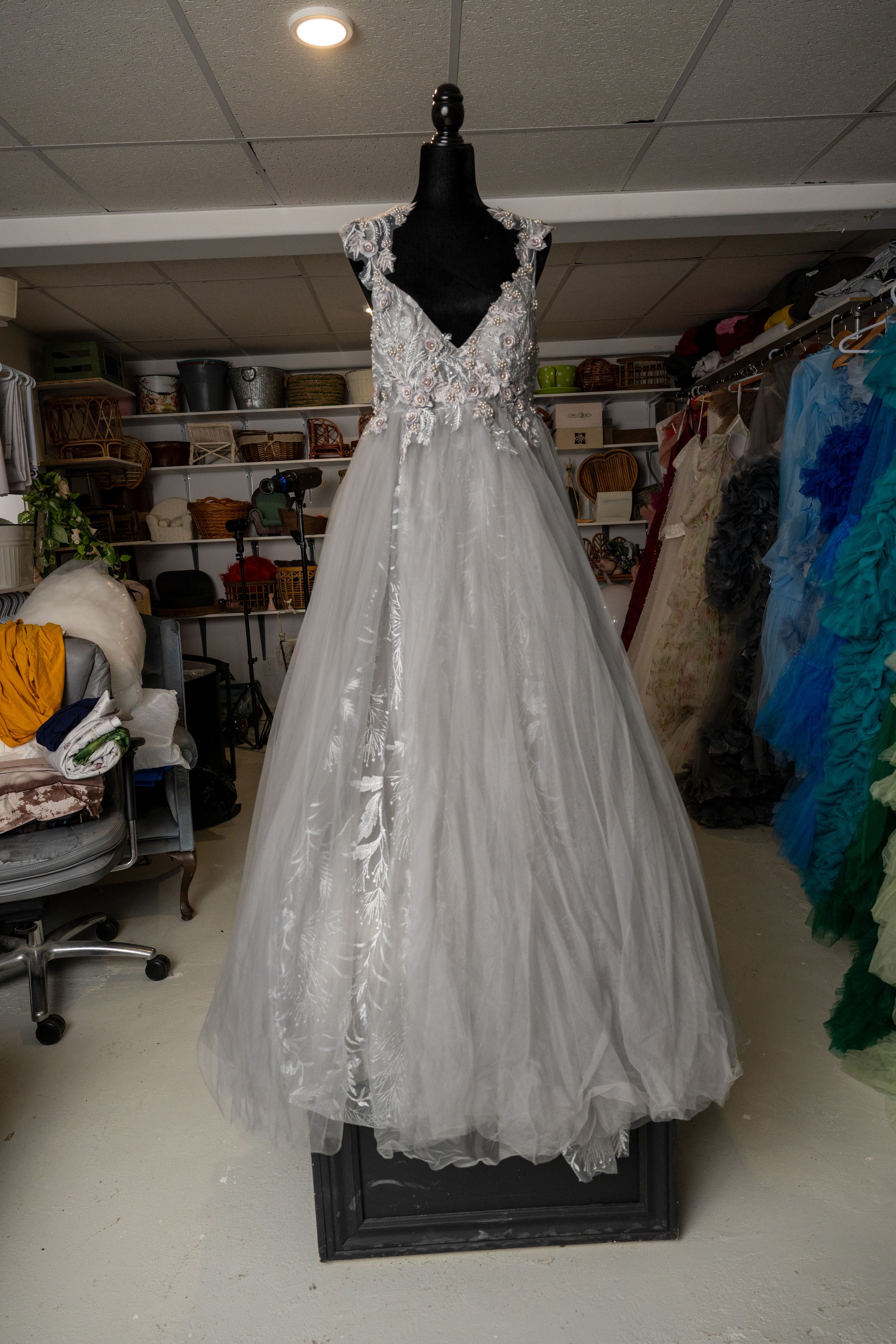A collection of white wedding dresses and formal gowns displayed on hangers in a retail store setting.
