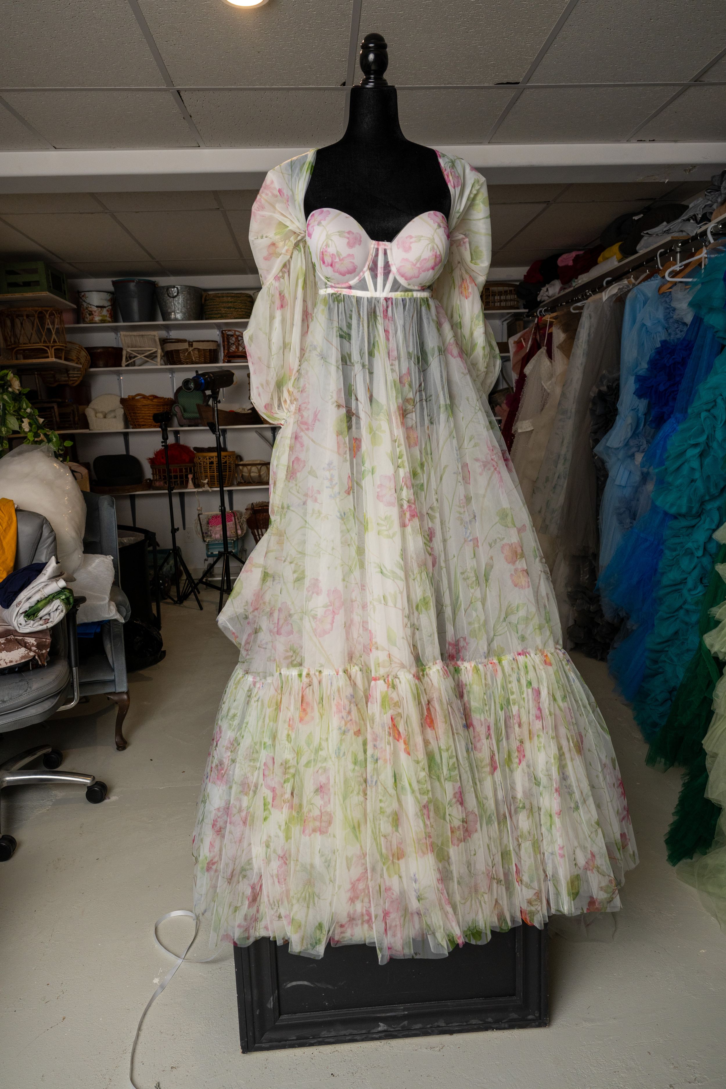 A floral print tulle dress with a sweetheart neckline displayed from multiple angles in a clothing storage area.