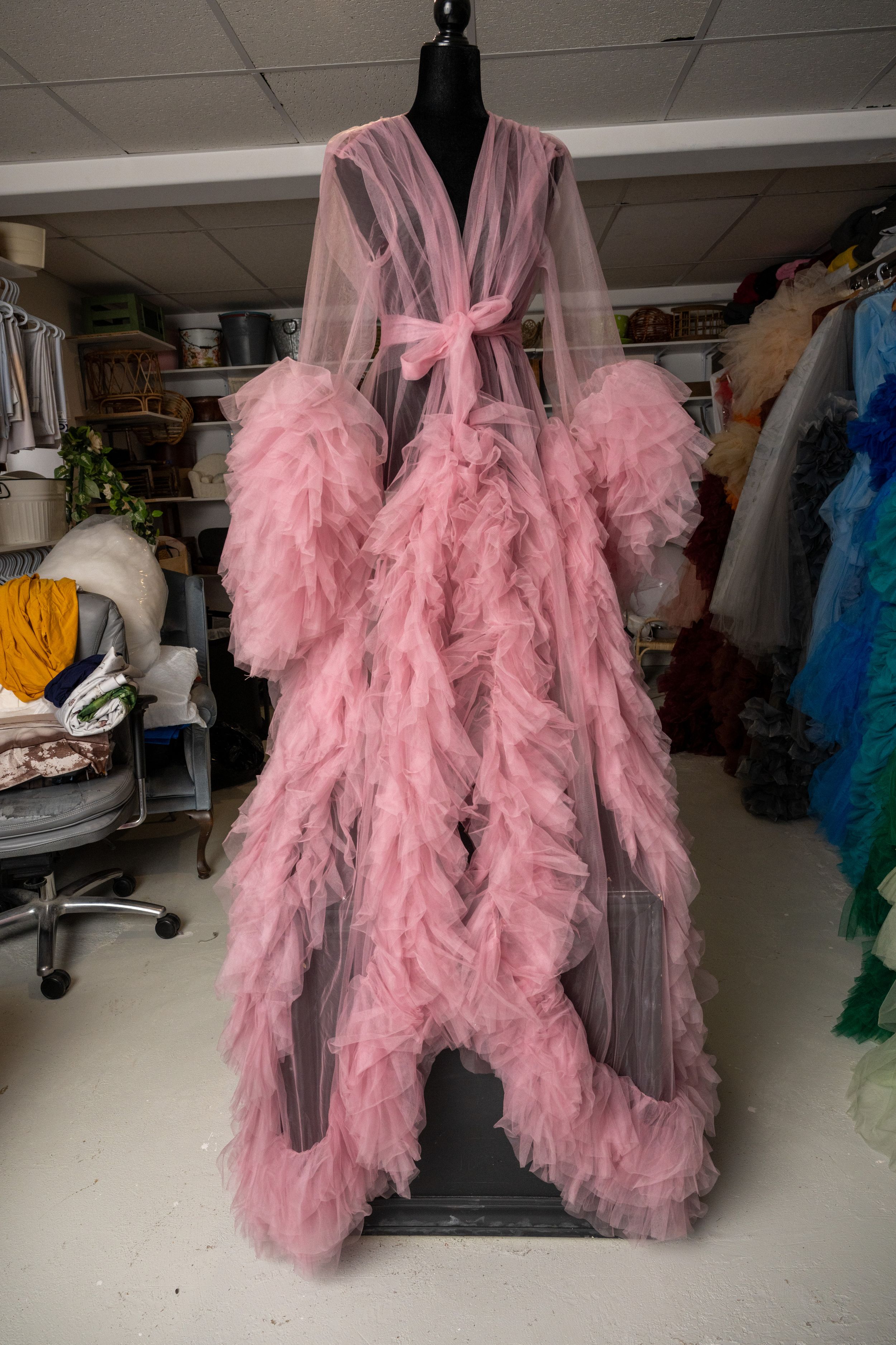 Pink tulle fabric dress displayed on mannequin in fashion workshop showing various angles and construction details.