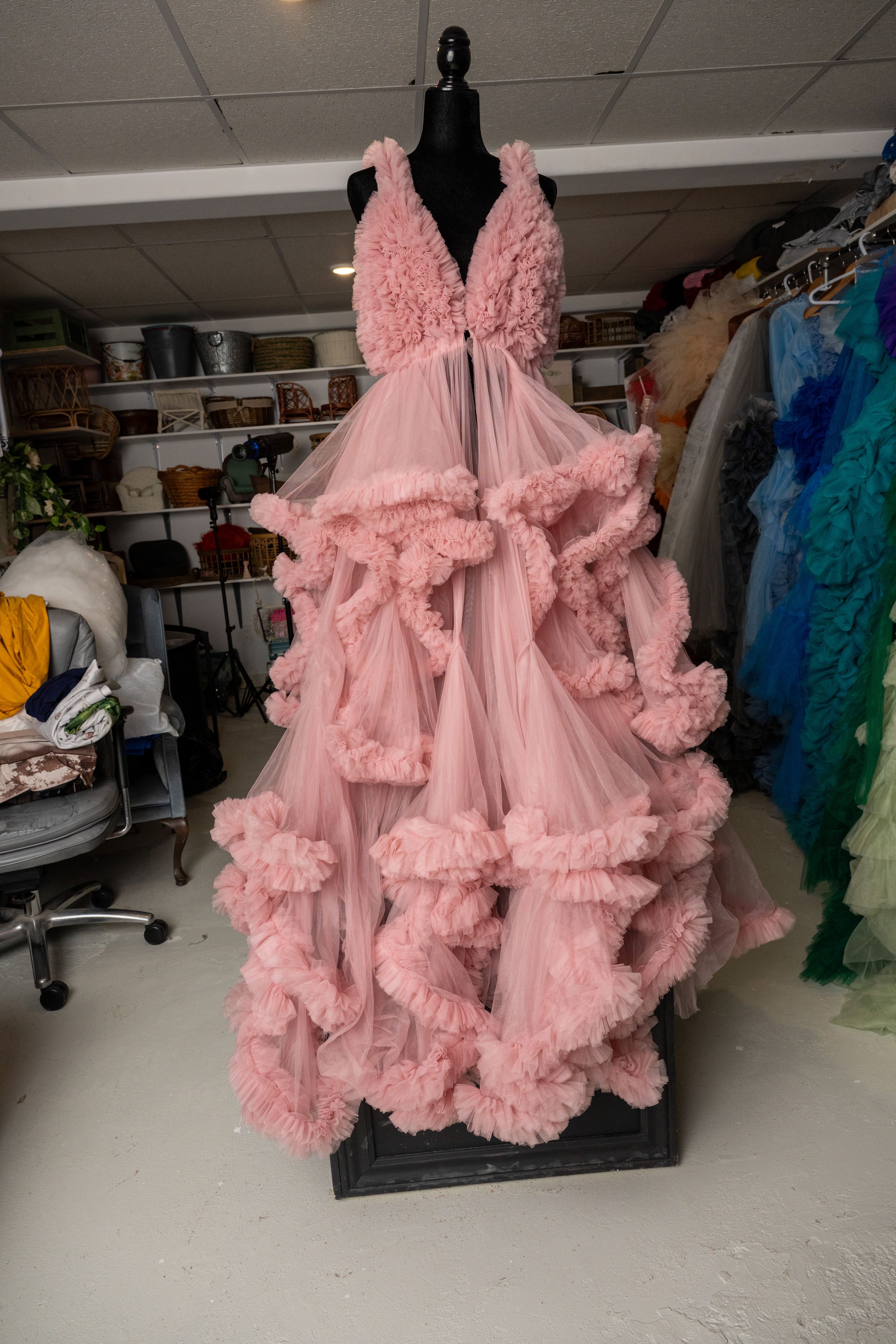 Pink ruffled tulle gown with dramatic layered details displayed in a fashion studio setting.