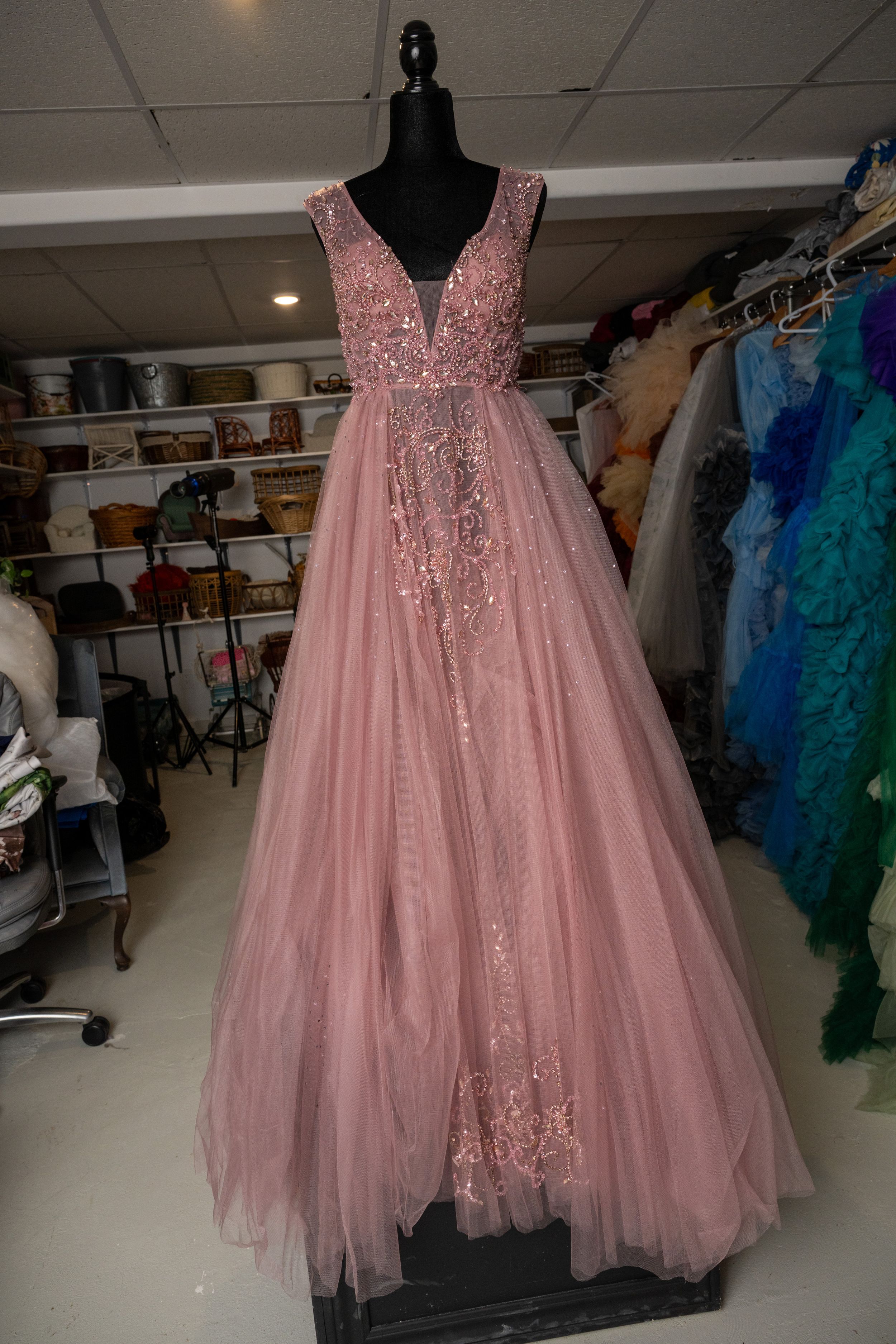 Pink tulle ballgown with sequined bodice displayed on mannequin in formal dress boutique showroom.