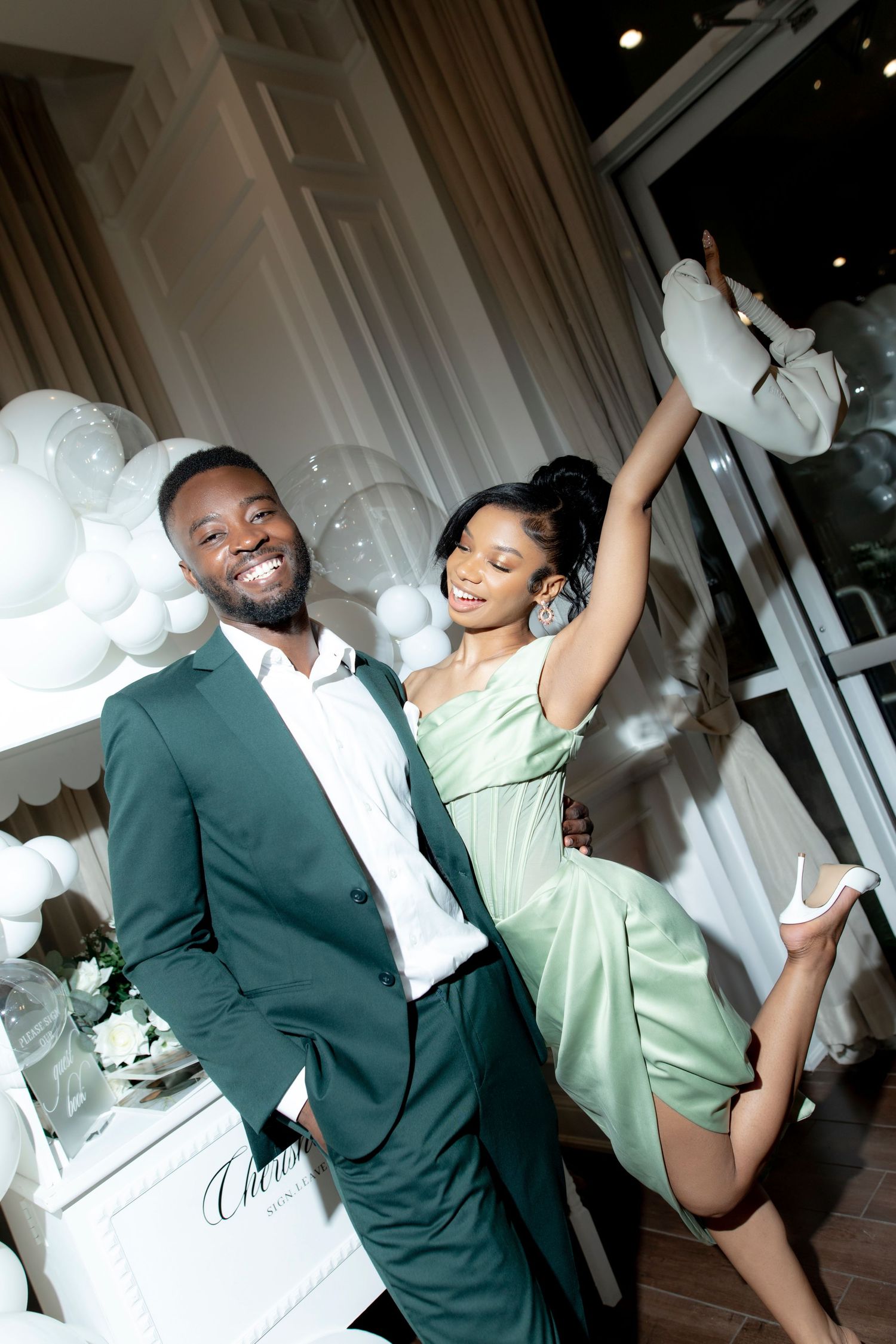 Wedding couple walks down the aisle at an indoor ceremony decorated with white chairs and dandelion-like light fixtures.