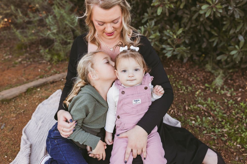 A family wearing coordinating outfits poses together outdoors for a fall photo session in nature.